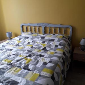 uma cama com uma colcha azul e amarela em Gîte les petits loups em Thoury
