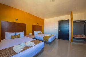 Hotel Maria del Rocio في فيراكروز: سريرين في غرفة الفندق بجدران صفراء