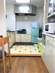 eine Küche mit einem blauen Kühlschrank und Fliesenboden in der Unterkunft Tokyo Kakan in Tokio