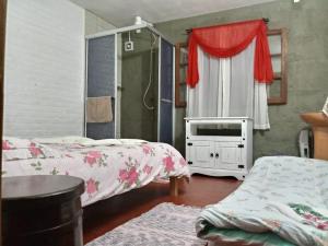 a bedroom with two beds and a window with a tv at Recanto dos Pioneiros in Nova Petrópolis