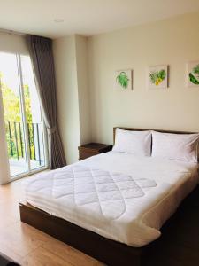 a bedroom with a large white bed and a window at TEAK VILLA in Bangkok