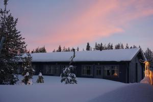 Una casa nella neve con una persona che regge un albero di Natale di Lapin Lumilomat ad Äkäslompolo