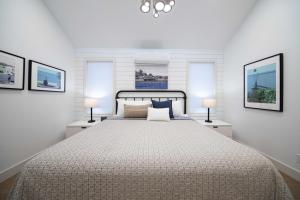 a white bedroom with a large bed with two lamps at Newsroom Suites in Wellington