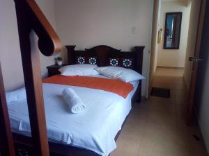 a bedroom with a bed with white sheets and an orange blanket at Casa Alar Del Conde in San Gil