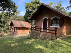 a small brick house with a window and a building at Chalés Lua de Mel in Monte Verde