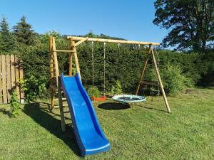 a playground with a blue slide in a yard at Górska Latarnia in Miedzygorze
