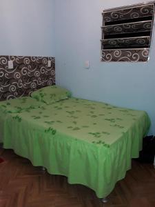 a bed in a room with a green blanket on it at Kitnet novo, completo com AR, 10km da Igreja do Bonfim e 13km do Pelourinho, Centro. in Salvador