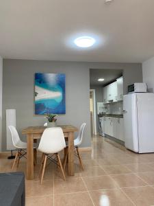 a kitchen with a table and a white refrigerator at Oasis Fuerteventura Beach Apartments in Corralejo