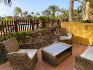 un patio con sillas de mimbre, una mesa y una valla en Oasis Fuerteventura Beach Apartments, en Corralejo