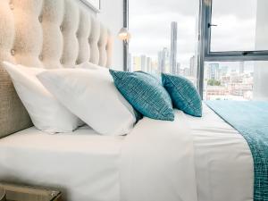 a bed with white and blue pillows and a window at Apartments on Connor in Brisbane