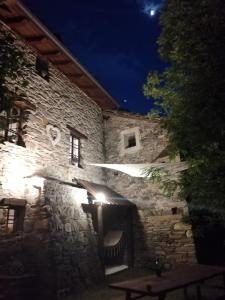 un edificio de piedra por la noche con una mesa delante en La Casetta di Lele e Schina, en Arvier