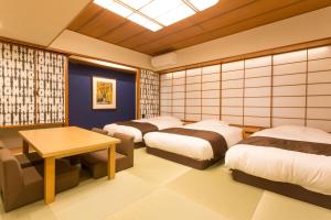 Osaka Riverside Hotel في أوساكا: غرفه فيها اربع اسره وطاولة فيها