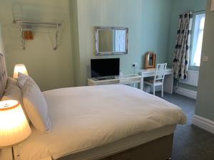 a bedroom with a bed and a desk with a television at Shrubbery Guest House in Worcester