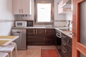Elle comprend une petite cuisine avec des placards en bois et une fenêtre. dans l'établissement Le Poulpe bleu Fuerteventura chic and relax, à Puerto del Rosario