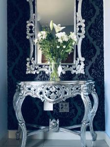 un jarrón de flores sobre una mesa con un espejo en 2 on ZK Matthews Guesthouse en Mthatha