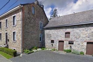 un grande edificio in mattoni con due porte garage di La cense du vieux frêne a Sainte-Ode
