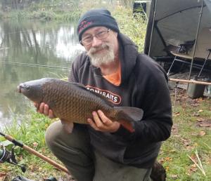 a man holding a fish in front of a river at "George's" lakeside wooden tipi in Sudbury