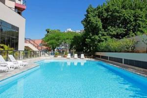 a large swimming pool with white chairs and a building at Flat Space Valley - Para 2 Pessoas in São José dos Campos
