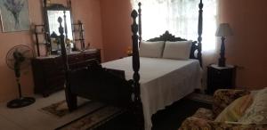 1 dormitorio con cama con dosel y silla en Suzette's Homestay, en Lucea