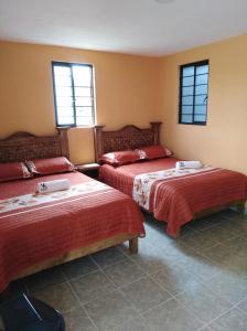a room with two beds and two windows at Hotel Posada Victor Antonio in Zacatlán