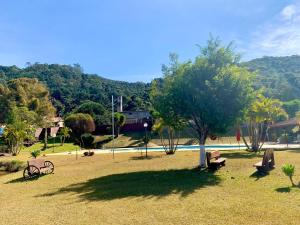 un parque con un árbol y una piscina en Hotel Nascentes da Serra en Poços de Caldas