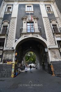 a building with an arch with a clock on it at Old Town Apartments Catania in Catania