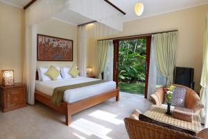 una camera con letto, TV e divano di The Buah Bali Villas a Seminyak