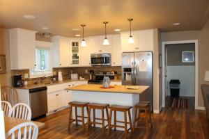 a kitchen with white cabinets and a island with bar stools at Cedar Court Inn in Fish Creek