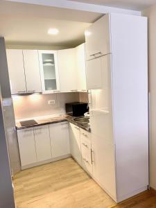 eine weiße Küche mit weißen Schränken und einem Kühlschrank in der Unterkunft Apartman La Promenade Zlatibor in Zlatibor