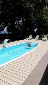 eine Person in einem Pool neben zwei Stühlen in der Unterkunft Cahuita Inn in Cahuita