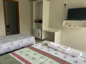 um pequeno quarto com uma cama e uma televisão em Pousada Toca do Ceará em Regência