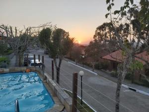 a swimming pool with a sunset in the background at Gravatá Country House in Gravatá