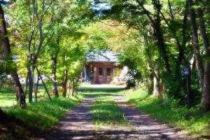a path through a forest with a house in the background at Minami Aso Luna Observatory Auberge Mori no Atelier in Minami Aso