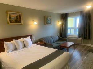 ein Hotelzimmer mit einem Bett und einem Stuhl in der Unterkunft Hotel and Suites Les Laurentides in Saint-Sauveur-des-Monts