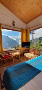 ein Wohnzimmer mit einem Bett und einem großen Fenster in der Unterkunft Mountain Rover Auli Resort in Jyotirmath