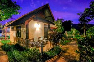 a house with a table and chairs in front of it at Pai Tewdoi ปาย ทิวดอย รีสอร์ท in Pai