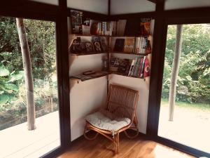 um quarto com uma cadeira e uma estante de livros com livros em Habuman Okinawa em Kunigami