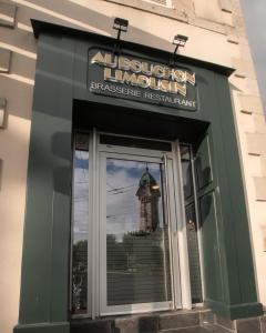 a sign for a restaurant with a reflection of a tower at Hôtel de la Poste in Limoges