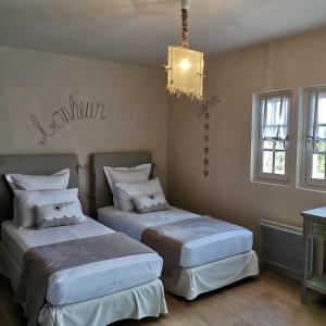 a bedroom with two beds and a chandelier at Au Clos de Mathilde in Sarlat-la-Canéda