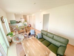 a living room with a green couch and a table at 2019新築 ! guest house Holoholo beach side in Ishigaki Island