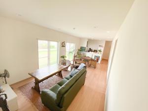 a living room with a green couch and a table at 2019新築 ! guest house Holoholo beach side in Ishigaki Island