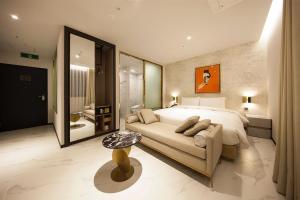 Nampo Hound Hotel Premier في بوسان: غرفة نوم بسرير واريكة وحمام