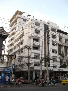 芭達雅中心的住宿－Highfive Hotel Pattaya，一座白色的建筑,前面停有摩托车