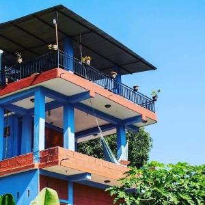 een blauw gebouw met een balkon erboven bij Begnas Lake Front guest house in Pokhara