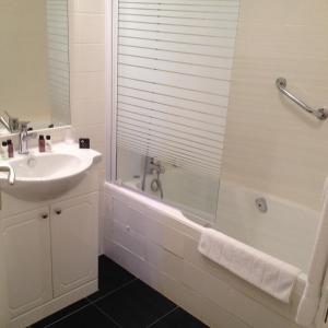 La salle de bains est pourvue d'une baignoire, d'un lavabo et d'une douche. dans l'établissement Logis Hôtel Restaurant La Bastide, à Villefranche-du-Périgord
