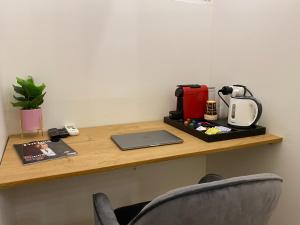 a desk with a laptop and a coffee maker on it at Rothschild Room in Petaẖ Tiqwa