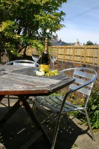 a table with a bottle of wine and two glasses on it at Garden Cottage in Prestwick