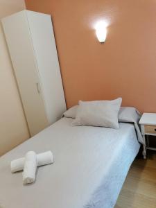 1 dormitorio con 1 cama y 2 toallas enrolladas en Hostal Hernan Cortes en Cáceres