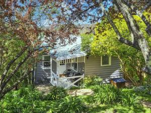 a small house with a porch and trees at Bonnie Brae Cottage in Hepburn Springs