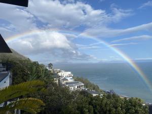 a rainbow in the sky over the ocean at Perhethian in Cape Town